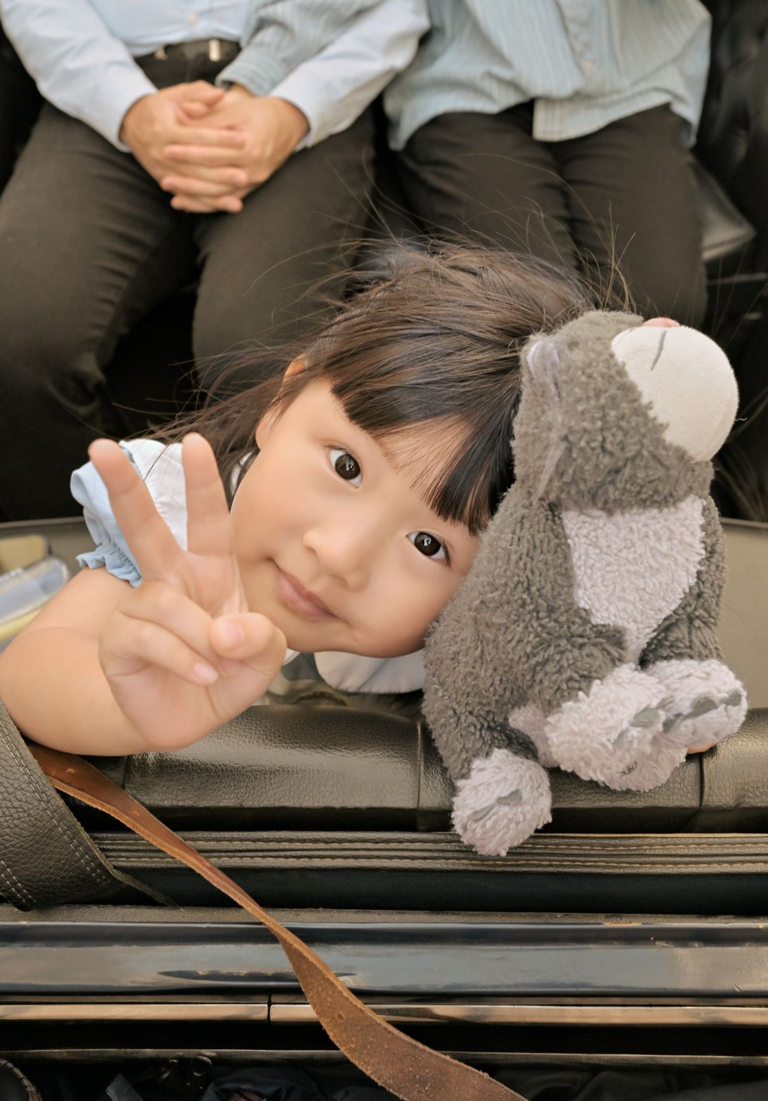 Kind zeigt das Peace-Zeichen mit Kuscheltier